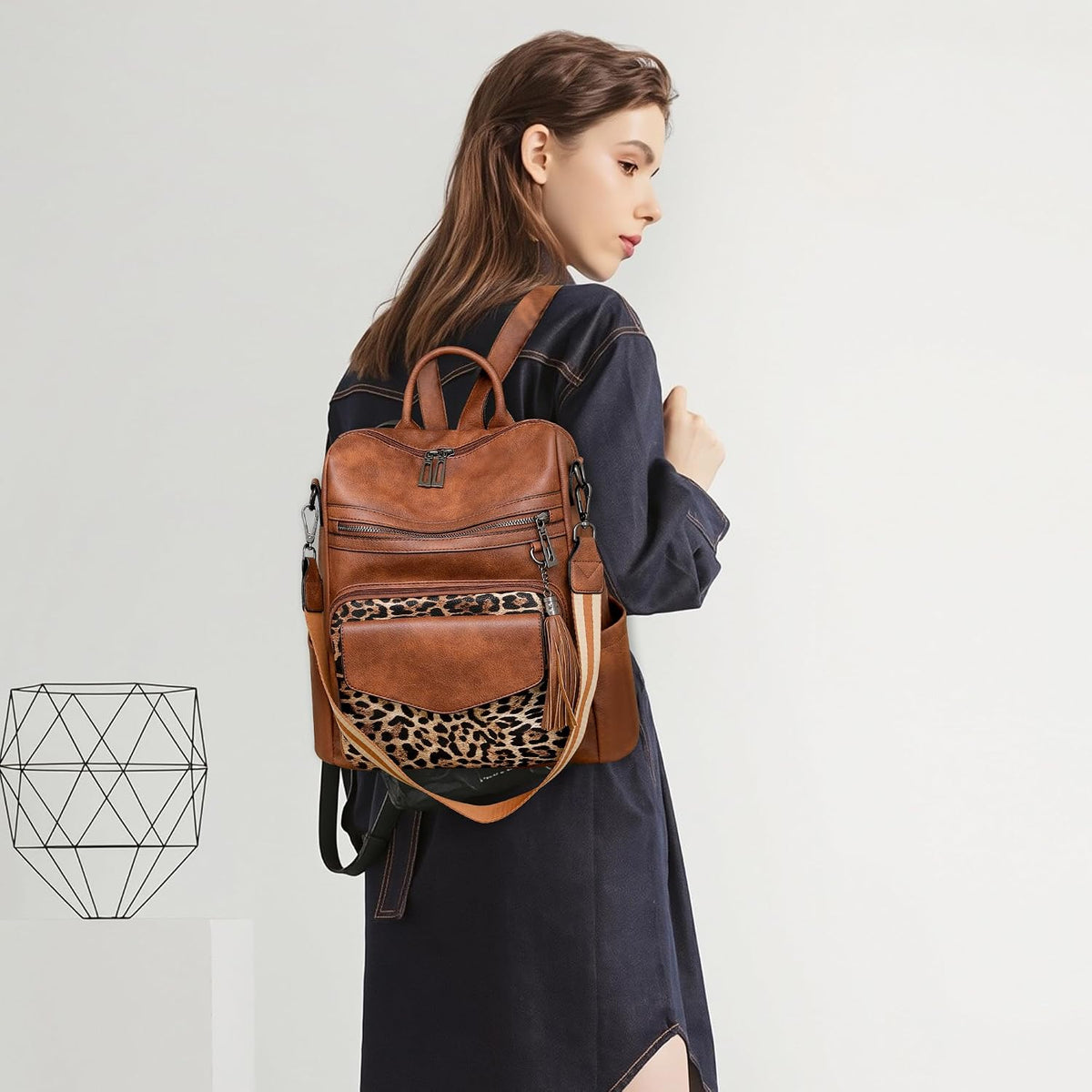 Woman wearing a brown vegan leather convertible backpack purse with a leopard print front panel and tassel zipper pull
